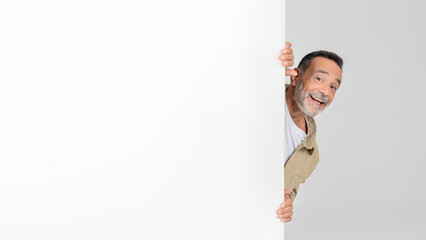 Man Peeking Out From Behind White Wall