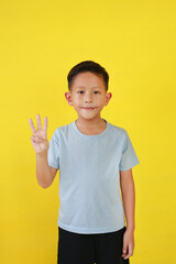 Portrait of Asian boy child show three fingers and looking straight while standing isolated on yellow background. - 793797371