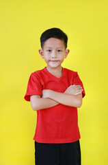 Portrait Asian little boy age about 7 years old standing and cross arms over chest looking straight at camera on yellow studio background. - 793797725