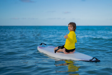 Child swimming on paddle board. Water sports, active lifestyle. Kid paddling on a paddleboard in the ocean. Child Paddle boarder. Summer Water sport, SUP surfing. Summer beach vacation.