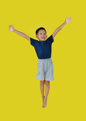 Happy Asian little boy child jumping in air over yellow studio background. - 793798193