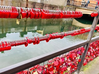 Many red love locks on a mesh fence on a bridge in Colmar France.