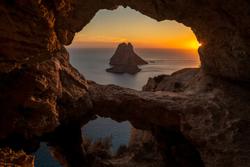 Es Vedra islet view through the rock holes of a cave at sunset, Sant Josep de Sa Talaia, Ibiza,...
