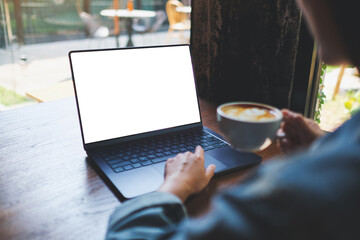 Mockup image of a woman working on laptop computer with blank white desktop screen while drinking coffee in cafe - 793812513