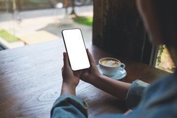 Mockup image of a woman holding mobile phone with blank desktop screen in cafe - 793812550