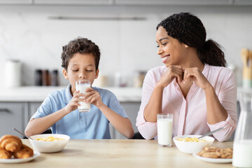 Mother watching son drink milk at breakfast