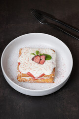 Belgian waffles with strawberry confit and cream sauce on dark background angle view