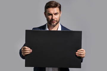 Information concept. Man with blank placard. Demonstrating copy space for your text or design. Man showing empty advertisement board on studio background. Blank placard with copy space, signboard.