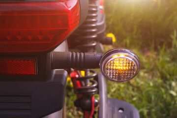 The right turn signal of scooter or bike parked on the roadside. The closeup view of direction safety signal with outdoors summer environment. - 793822911