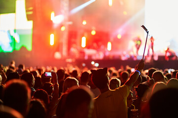 Music festival atmosphere with vibrant stage lights, enthusiastic audience enjoying live...