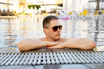 Handsome man in sunglasses relaxing in the pool.