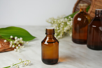 Lily of the valley, Convallaria majalis essential oil (extract, tincture, infusion, remedy) with fresh Convallaria flowers on light marble background. Side view.