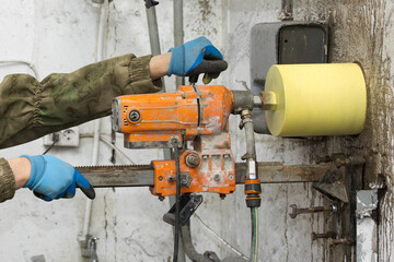 Worker using an electric drill to make a hole in a concrete wall, closeup - 793830981