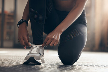 Fitness, woman and tying shoes in gym ready for workout, exercise and training for physical strength. Female person, sneakers and hands fixing laces on ground, floor and girl prepare for sports