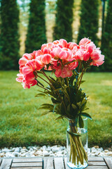 A bouquet of pink peonies, looking fresh and full of life. They are housed in a clear glass vase...