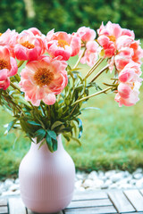 A pink vase textured with vertical ridges showcases a bouquet of vibrant pink peonies