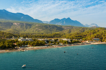 A tranquil aerial view of a Turkish seaside with calm waters meeting a lush peninsula and majestic mountains in the background