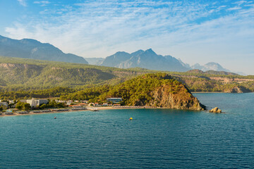 Scenic view of a Turkish seaside with calm sea, lush peninsula, and majestic mountains