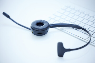 Headphones on desk, keyboard and business with call center, telemarketing and customer support in office. Workplace, headset and equipment with tech support, helpline and sales for insurance company