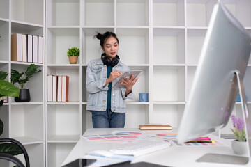 Female designer standing next to work desk, analyzing design, color placement for graphic design. Choose colors for working with your computer at your desk.
