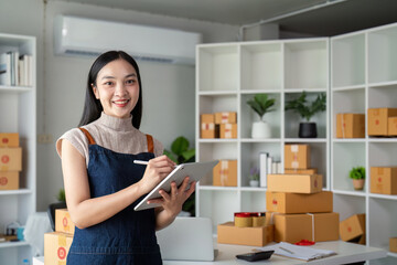 Young business woman asian working online ecommerce shopping at her shop. Young woman sell prepare parcel box of product for deliver to customer. Online selling