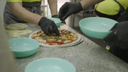 Hands garnishing pizza with fresh ingredients