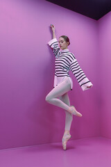 young ballerina in white tights and a half-skirt poses ballet steps standing on pointe shoes