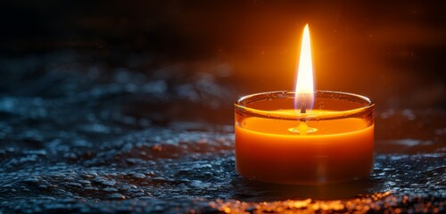 A lit candle casting a warm glow against a dark backdrop.