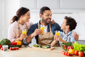 Cheerful African American family drinking fresh orange juice