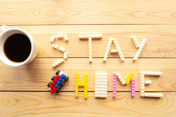 Phrase Stay at Home from toy constructor and coffee cup on wooden background. Quarantine concept