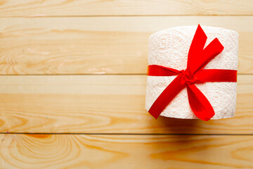 toilet paper roll wrapped in gift bow on wooden background. Covid19 concept. Copy space for the text