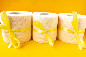 toilet paper rolls wrapped in gift bows on bright yellow background. Covid19 concept.