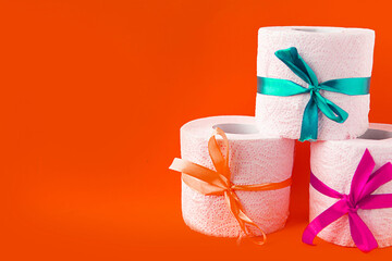 toilet paper rolls wrapped in gift bows on bright orange background. Covid19 concept. Copy space for the text