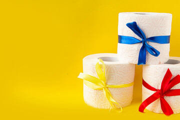 toilet paper rolls wrapped in gift bows on bright yellow background. Covid19 concept. Copy space for the text