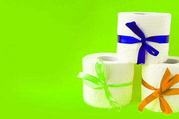 toilet paper rolls wrapped in gift bows on bright green background. Covid19 concept. Copy space for the text