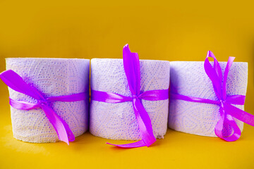 toilet paper rolls wrapped in gift bows on yellow background. Covid19 concept.