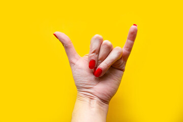 Closeup view of female hand forming gesture call me. Isolated on bright yellow background. Copy space for the text