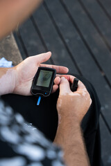 Men checking their sugar levels using a lancet pen and a glucometer in the city