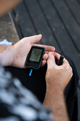 Men check their sugar levels using a lancet pen and glucometer