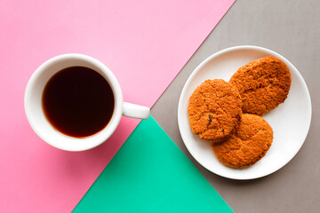 Coffee cup and oatmeal cookies on geometric color background. Minimal concept