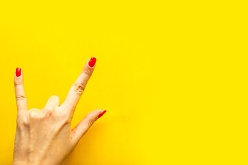 Woman's hand shows a gesture Rock over bright yellow background. Copy space for the text