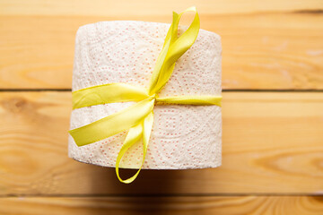 toilet paper roll wrapped in gift bow on wooden background. Covid19 concept.