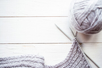 Knitting, needles and ball of gray thread on wooden background. Copy space for the text