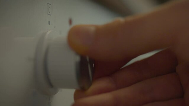 The hand of a young chef presses a button on the dashboard of the oven, turning it on to prepare delicious dishes. The oven in a modern kitchen is ready for use