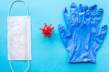 Medical gloves, red model virus and mask on blue background. Covid-19 concept
