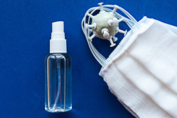 Medical mask and hand sanitizer on blue background. Coronavirus concept