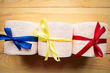 Toilet paper rolls with gift bows on wooden background. Quarantine concept.