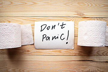 Toilet paper rolls and card with message Don't Panic on wooden background. Quarantine concept