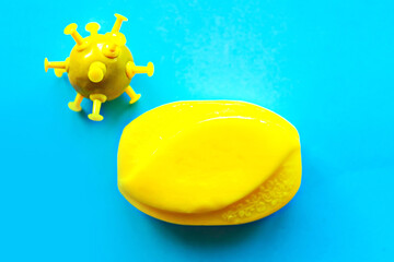Bright yellow soap bar and positive virus on blue background. Covid-19 concept