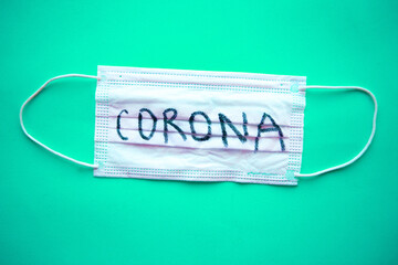 Medical mask with word Corona on blue background. Covid-19 concept